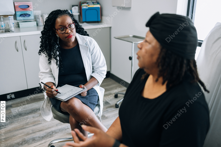 Black female doctor consults woman with head covering