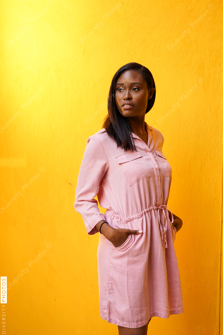 Young woman standing against yellow background
