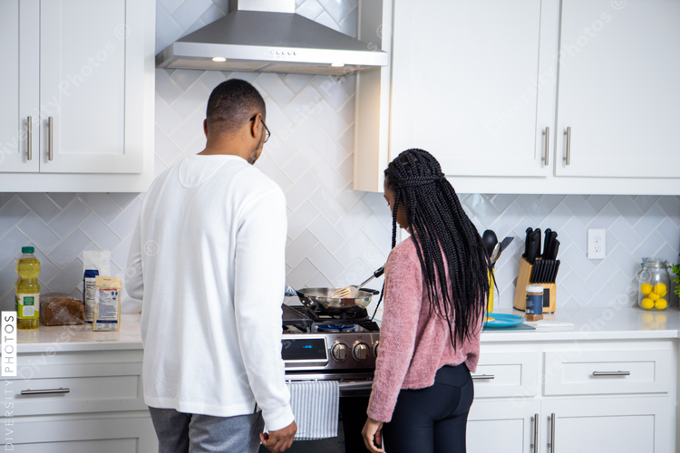 African American father and daughter cooks in kitchen