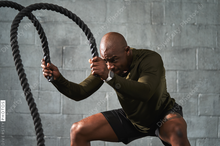 Black man training with battle ropes in crossfit