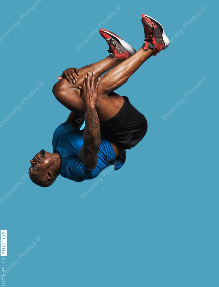 Black man jumps and does backflip on blue background