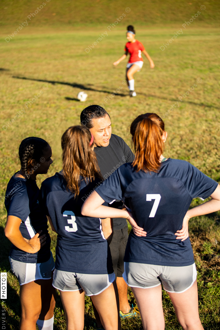 Teenage soccer coach teaches plays with female team