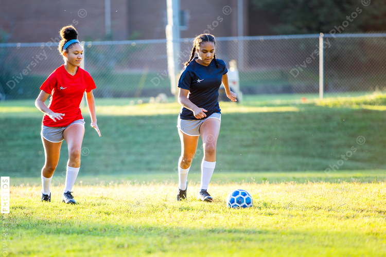 Teenage girl soccer players running after ball