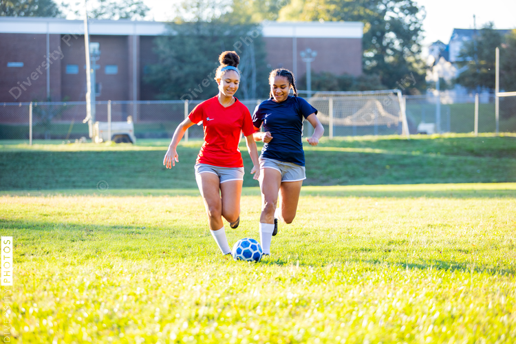 Teenage girl soccer players running after ball