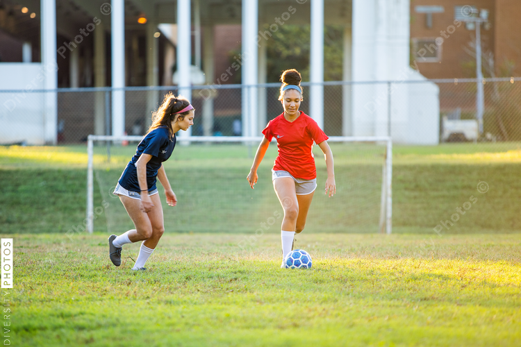 Teenage girl soccer players running after ball