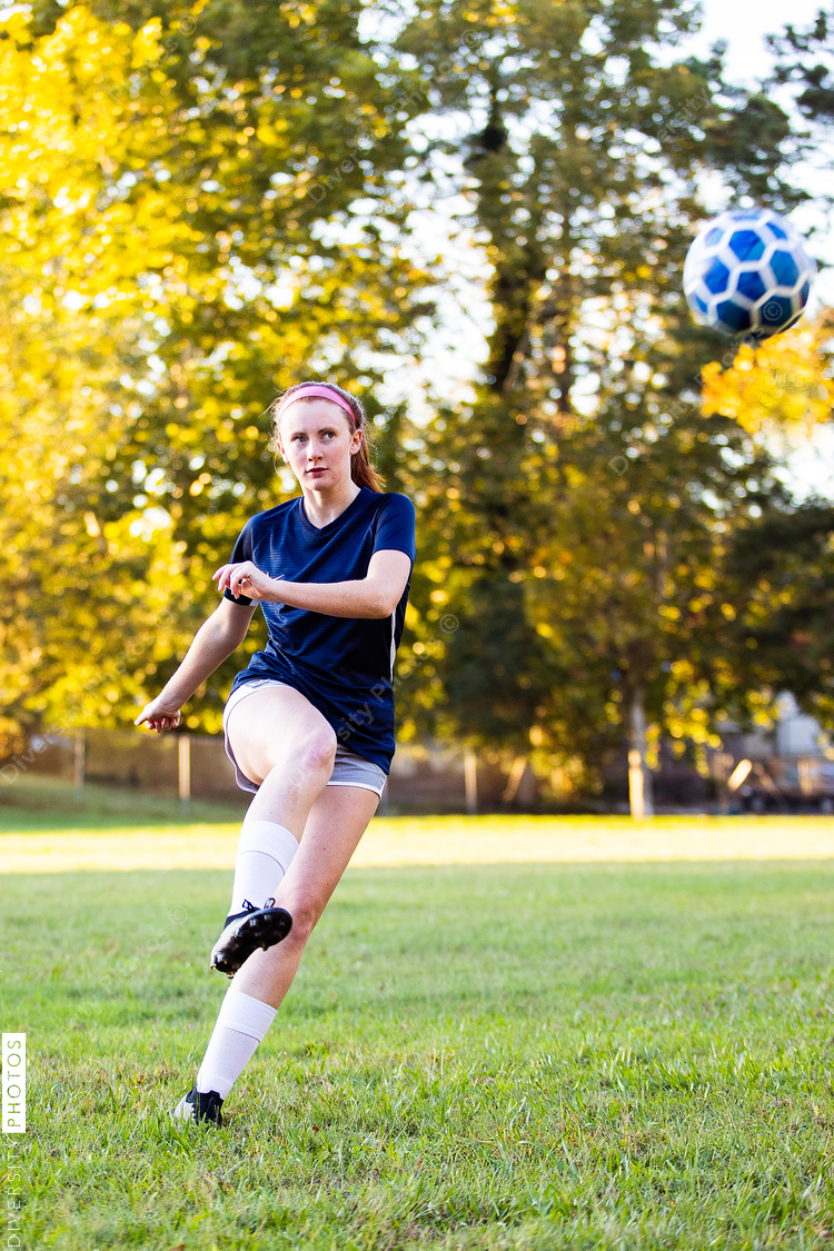 Teen girl soccer player kicking ball