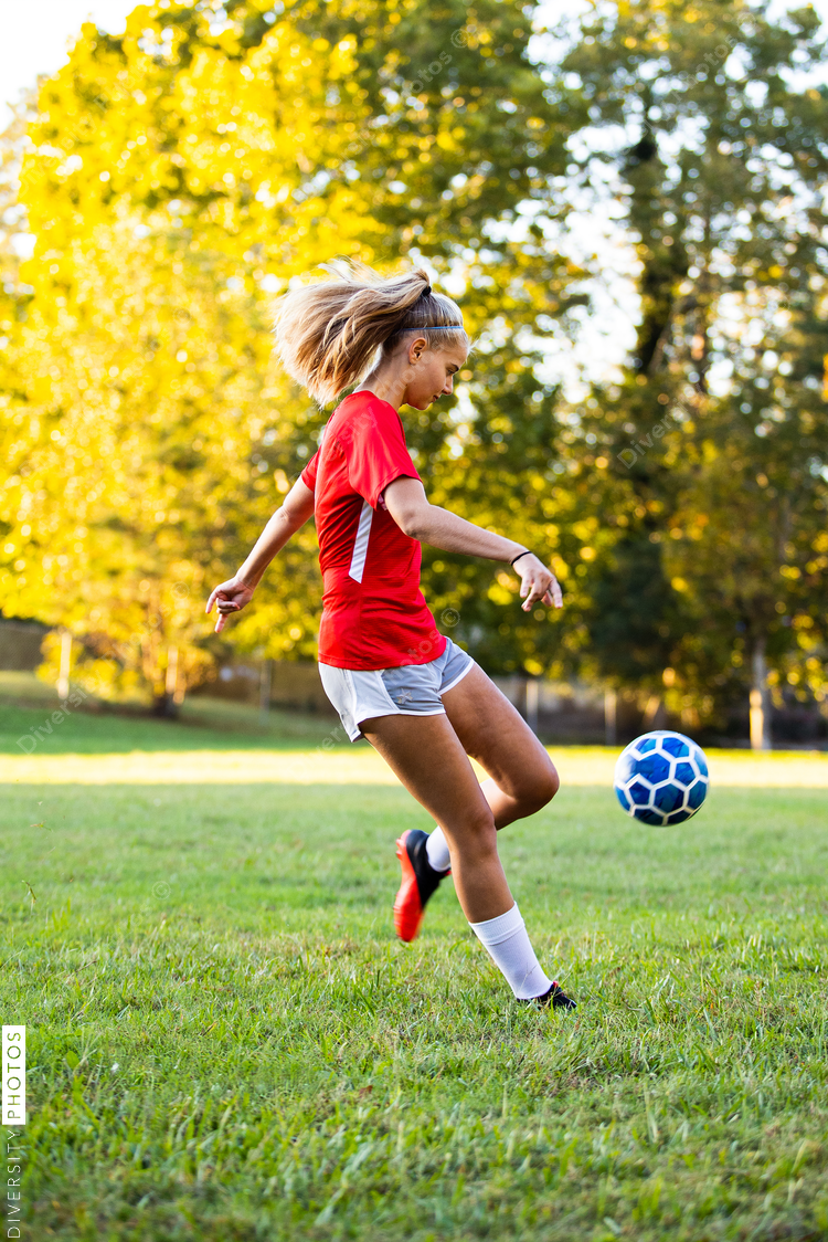 Teen girl soccer player kicking ball