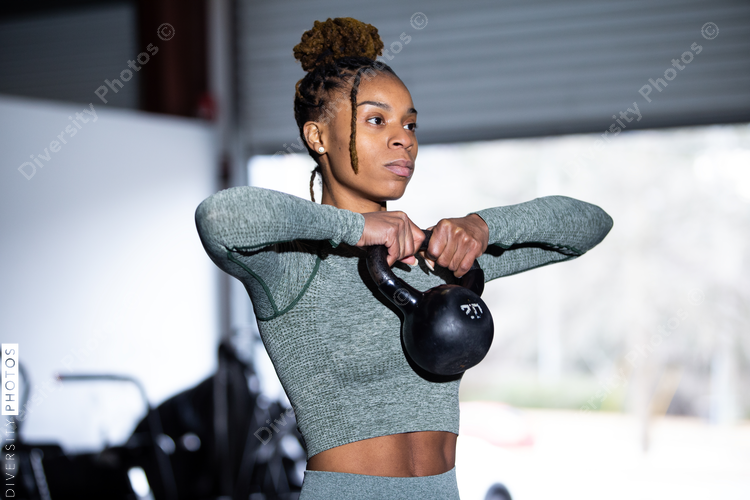 Black woman does fitness workout kettlebell upright row Diversity Photos