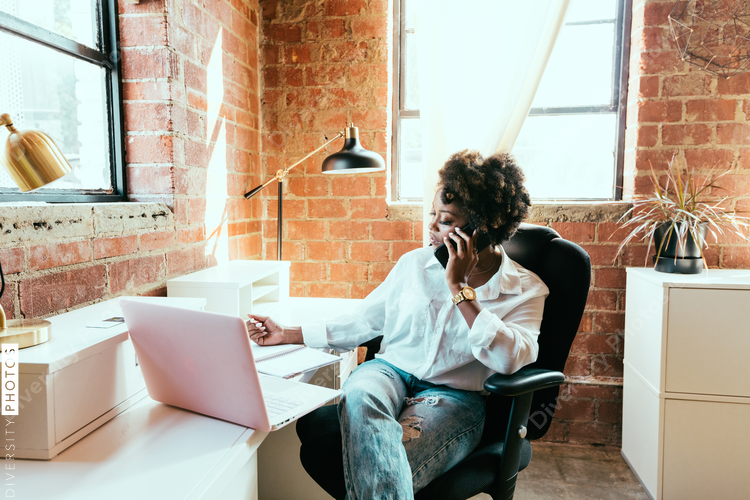 Woman writing notes while talking on mobile phone