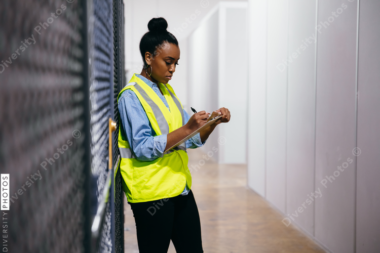 African American woman in datacenter surveying warehouse is secure