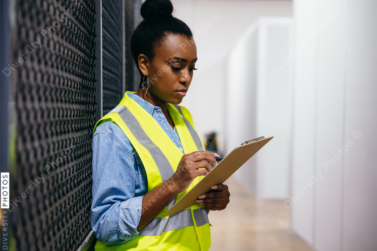 African American woman in datacenter surveying warehouse is secure