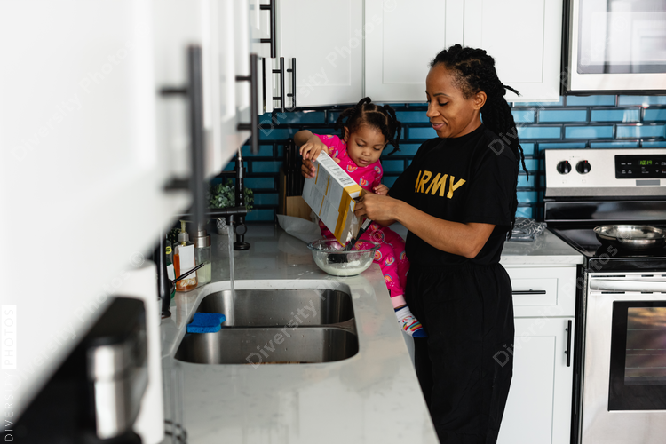 Black army mother cooks breakfast in kitchen with daughter