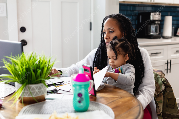 woman working from home with child on lap - Black woman working from home with toddler child sitting on lap ...