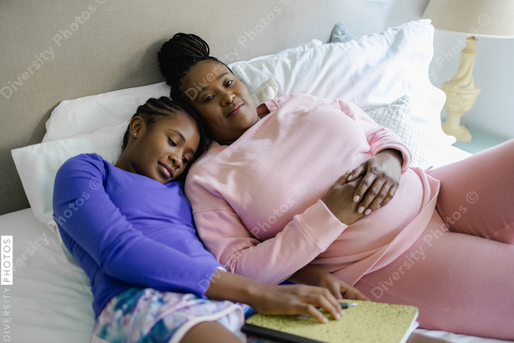 Mother and teenage daughter resting on bed