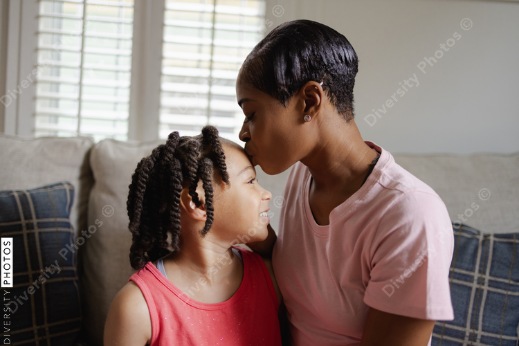 Mother and daughter sitting on sofa and being affectionate