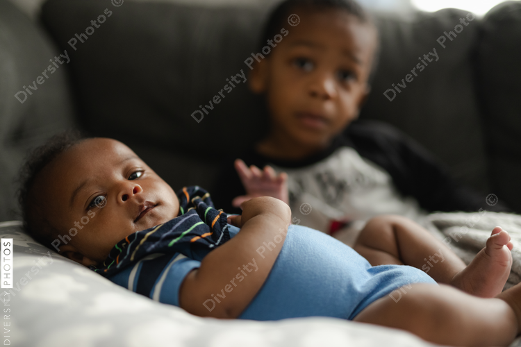 Black boys, siblings, sitting and laying on sofa