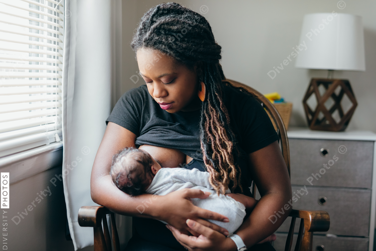 Black woman breastfeeding child at home
