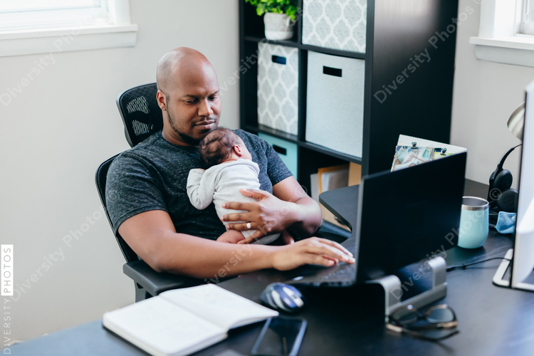 Black dad with newborn working from home