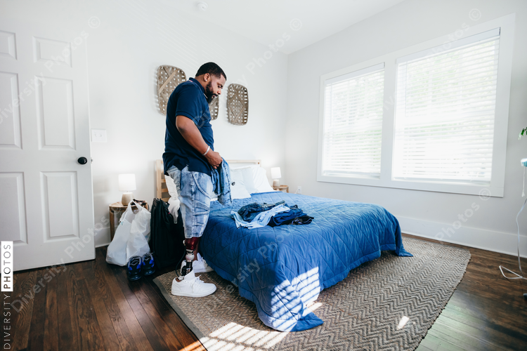 African American man with prosthetic leg doing chores, laundry, at home