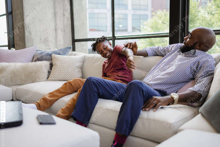 Playful father and son sitting on sofa