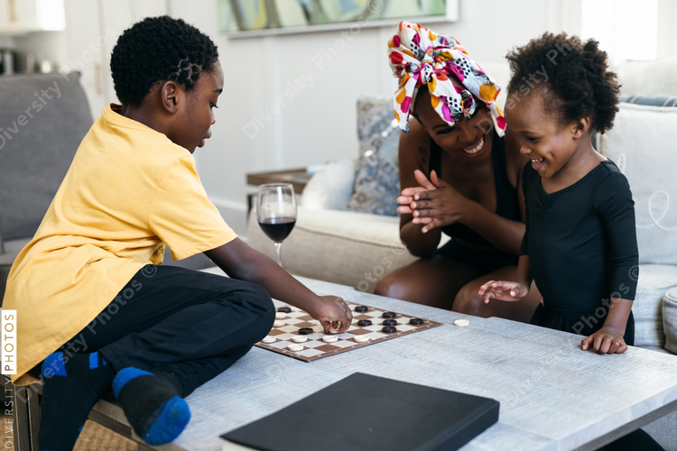 African American family playing checkers game at home