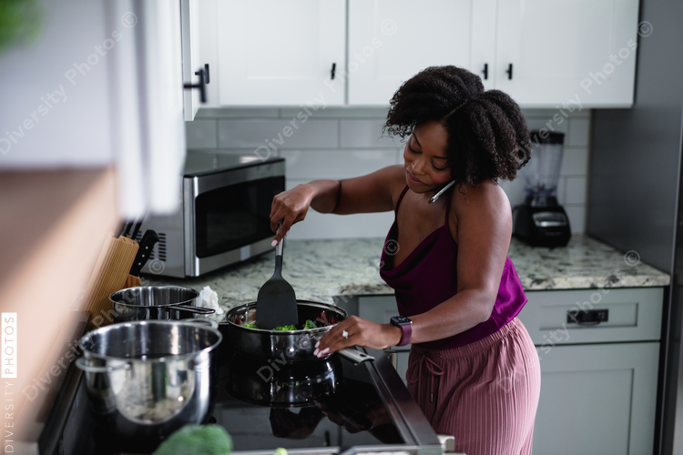 Black woman cooking at talking on phone, multitasking