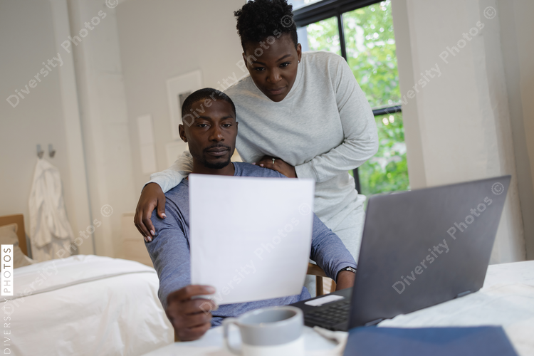 Black Couple reading document and using laptop