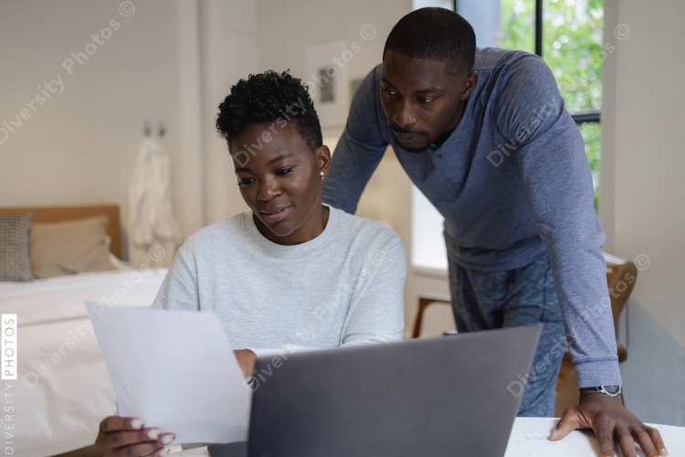 African American Couple reading document and using laptop