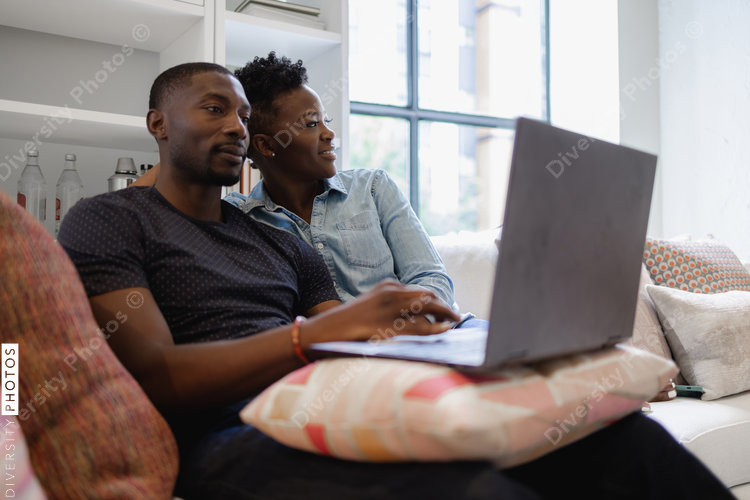 African American Couple sitting on sofa and using laptop