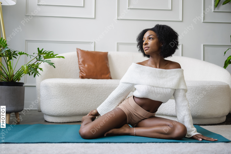 Young woman stretching in living room, Black, wellness