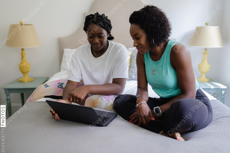 African American mother helps daughter with homework, on laptop