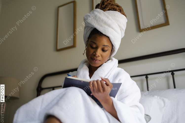 African American Woman in bathrobe writing in notepad