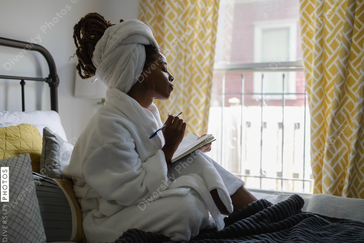 Black Woman in bathrobe writing in notepad