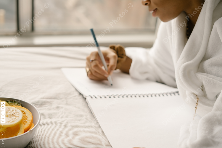 Black woman journaling at home in bed