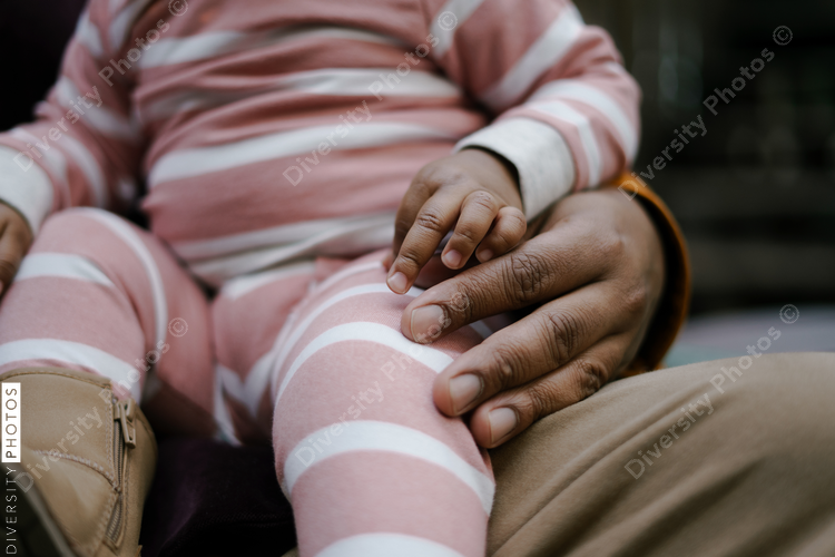 Black father and daughter sitting outdoors in backyard