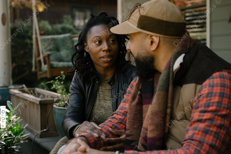 Beautiful black couple talking on front porch at home