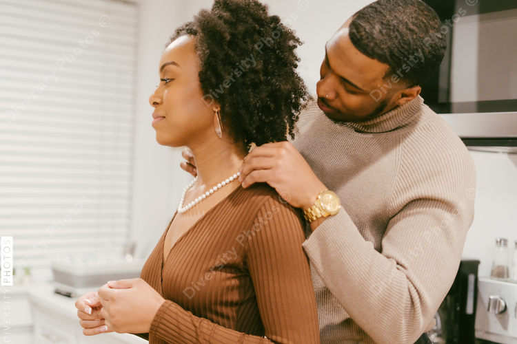 Black man puts anniversary gift necklace on girlfriend