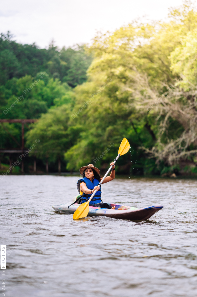 Woman kayaking on river with trees in background