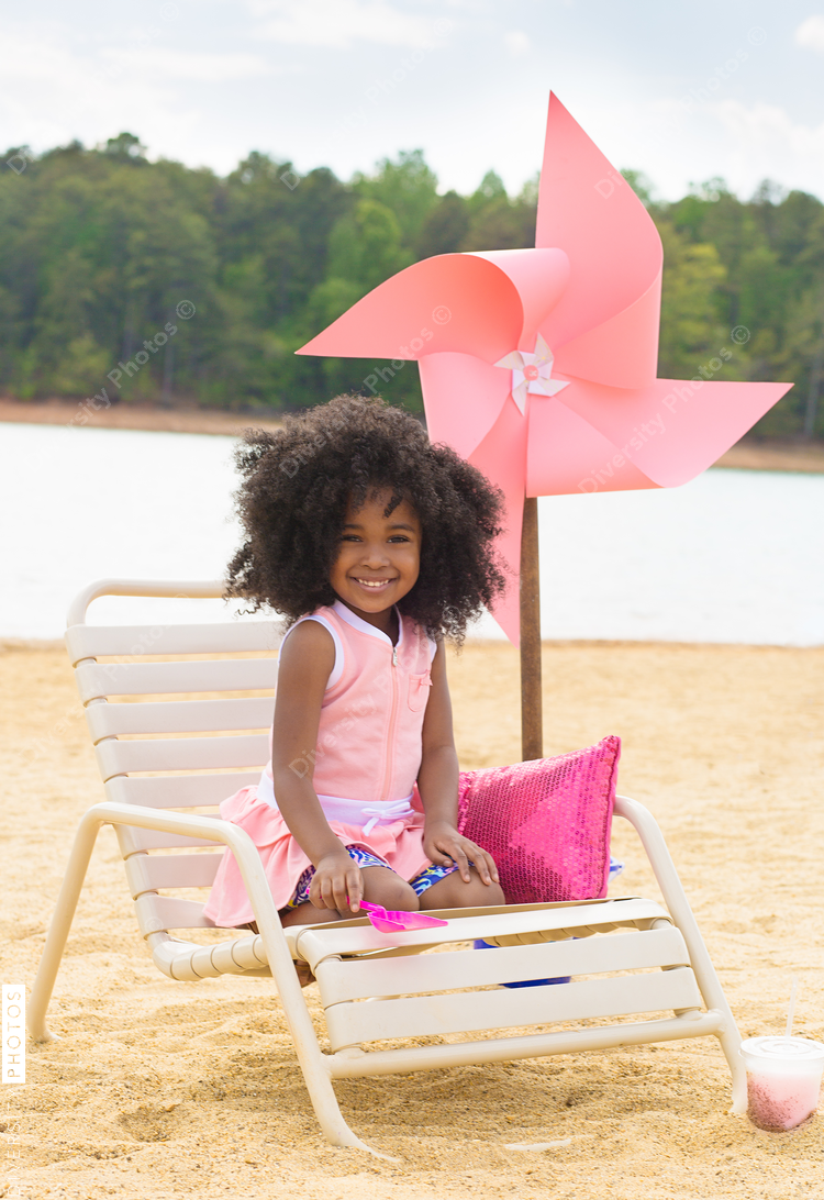 Portrait of smiling girl sitting on deckchair at beach