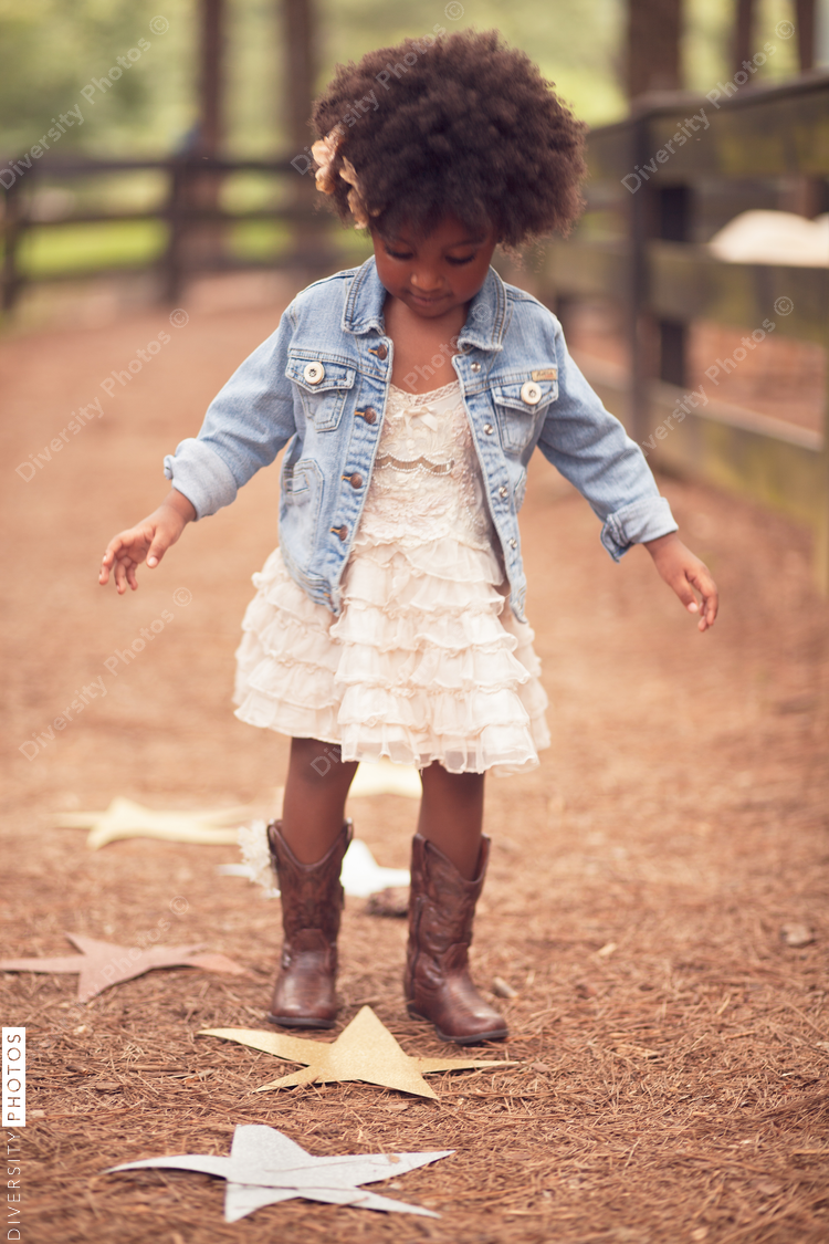Little girl looking down at paper stars on pathway