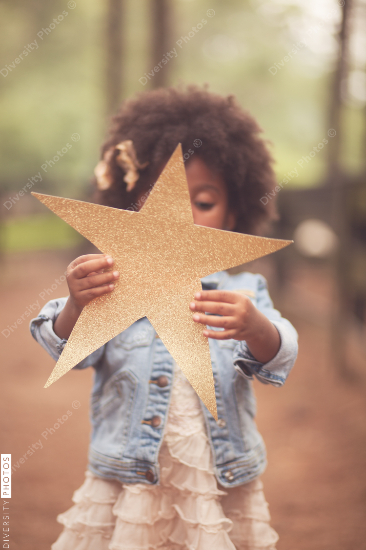 Little girl holding up sparkly paper star