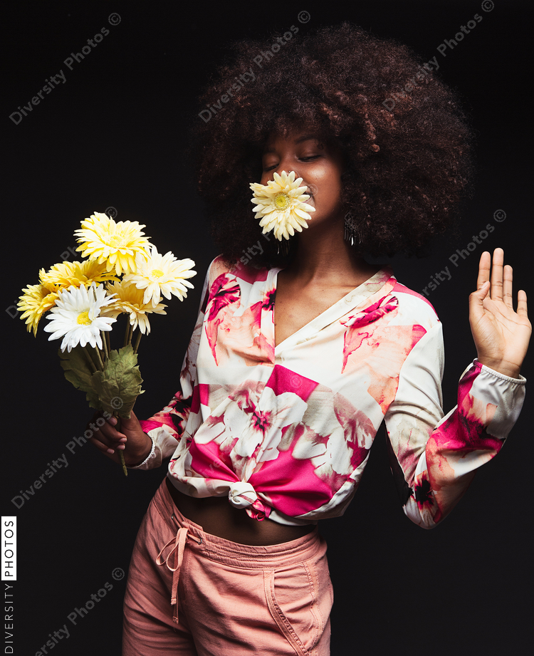 Young woman holding flower bouquet against black background