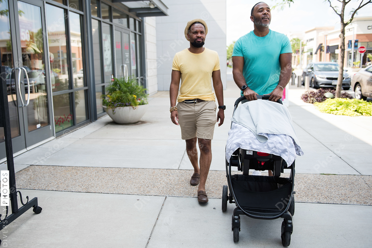 Men walking on road with baby stroller Diversity Photos