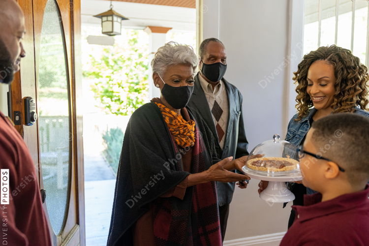 Grandmother and grandfather greet family for Thanksgiving wearing mask