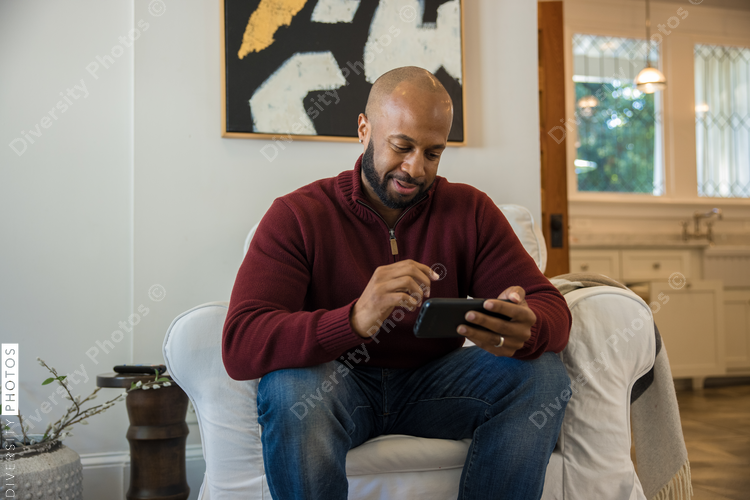 Black man watching sports on smartphone before thanksgiving dinner