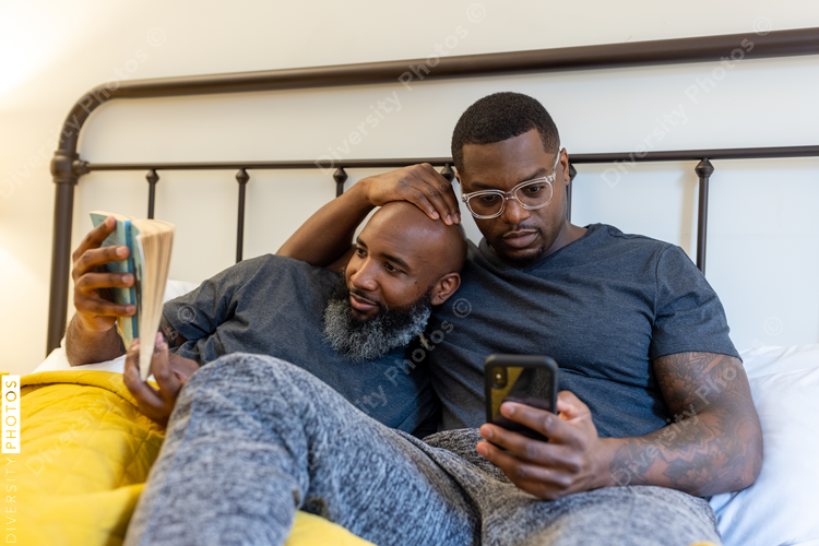 Black couple cuddling in bed at home, LGBTQ pride love connection