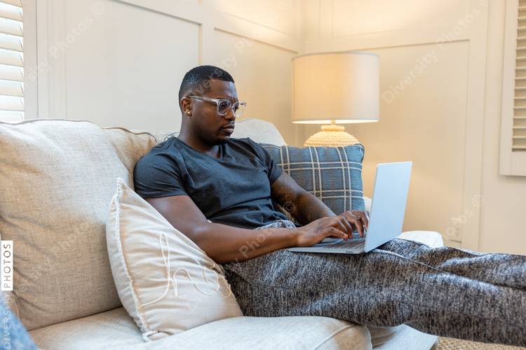 African American man working from home on laptop in living room, video chat conference call