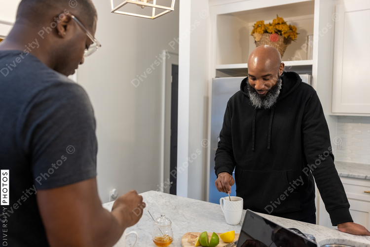African American same sex couple talking in kitchen at home