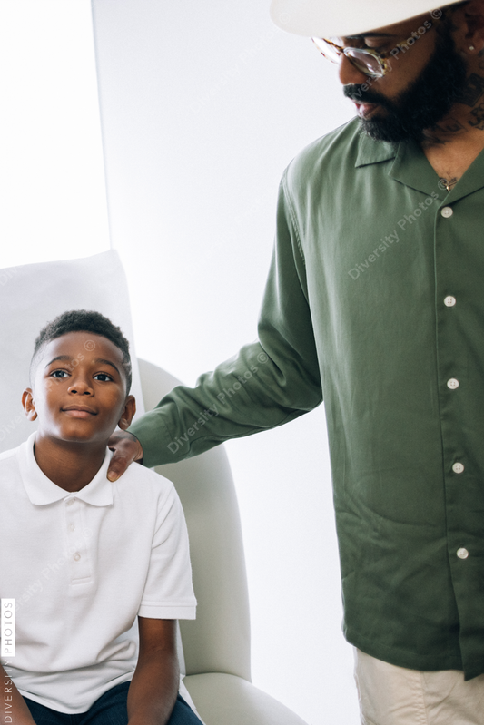 Black father and son wait in exam room for doctor