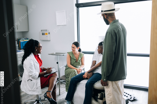 Black doctor consulting mixed race family at local physician practice